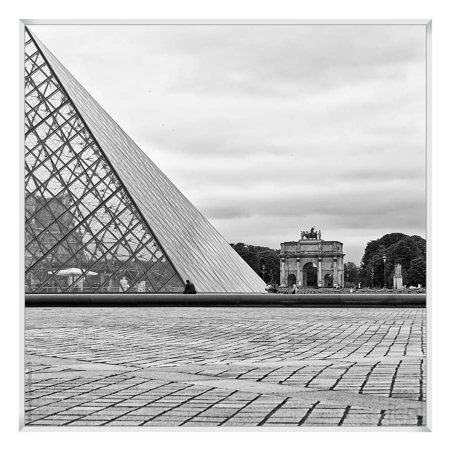 man seated in the continuation of an edge of the Louvre pyramid