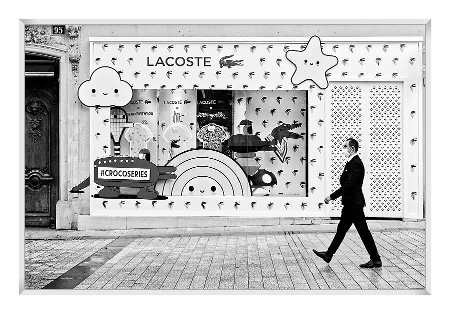 man in black walking past a Lacoste sign on the Champs Elysées