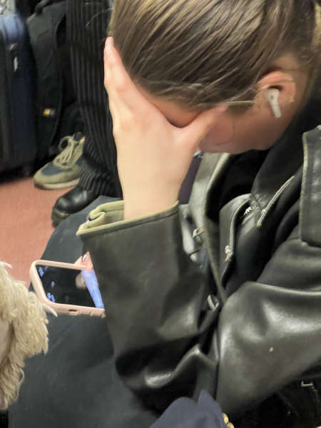 woman staring at her cell phone while holding her head