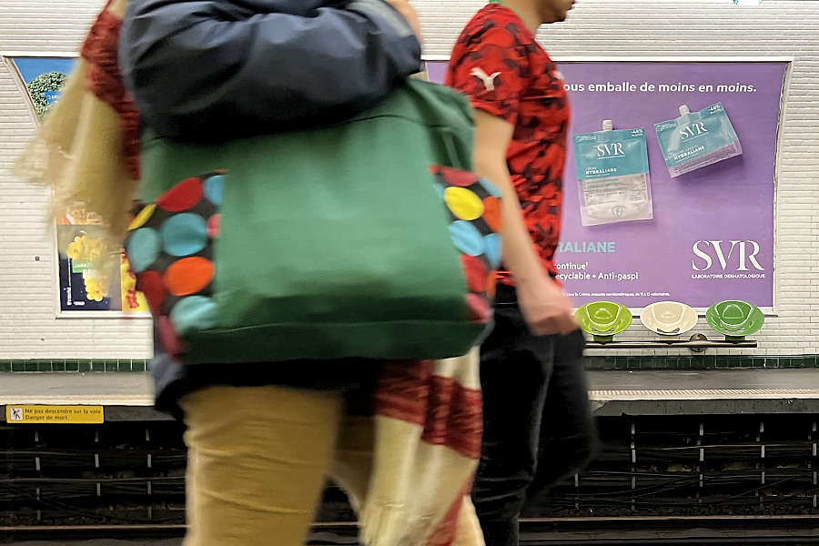 composition with a man walking past a text poster in the Paris metro