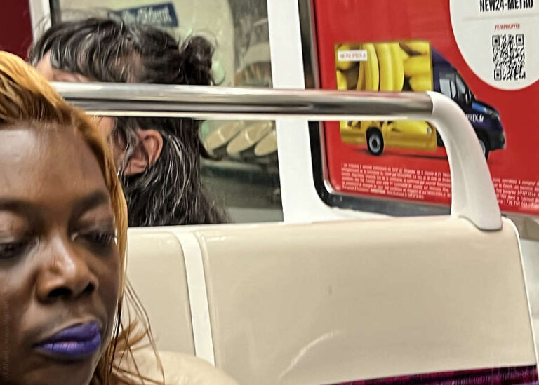 visage d'une femme noire devant une publicité représentant un camion rempli de bananes dans le métro parisien